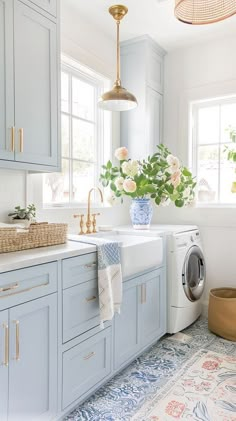 a washer and dryer in a kitchen with blue cabinets, white counter tops and floral rug