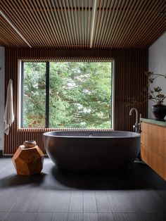 a large bath tub sitting under a window next to a wooden counter top in a bathroom