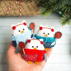 hand holding small christmas ornaments in the shape of owls with red, white and blue sweaters