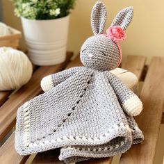 a crocheted bunny doll sitting on top of a wooden table