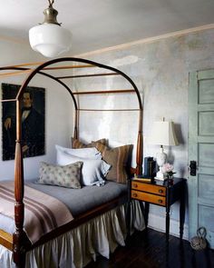 a bedroom with a canopy bed, dresser and painting hanging on the wall above it