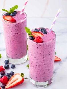 two smoothies with strawberries and blueberries in them