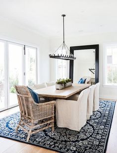 the dining room table is surrounded by wicker chairs and an area rug with blue accents