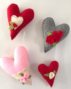 four felt hearts with flowers and leaves on them