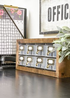 an office desk with drawers and a plant on it next to a sign that says office