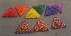 six different colored beads arranged in the shape of triangulars and triangles on a gray surface