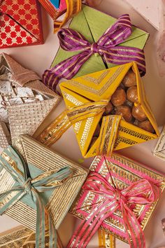 many different colored boxes with bows and ribbons on top of each one, all wrapped in gold foil