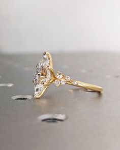 a gold ring with two pear shaped diamonds on it, sitting on top of a table