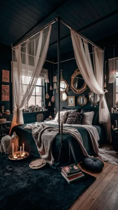 a canopy bed in a dark bedroom with white drapes hanging from the ceiling and candles on the floor