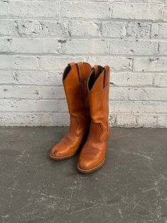 1970s cognac brown leather cowgirl style boots by Dexter. These casual boots are a timeless staple in any wardrobe. Pair with any sundress or wide leg trouser to add a subtle retro touch that will never go out of style. Featuring the perfect stacked heel & tapered toe! Made in the USA. Marked as a women's size 7. In great vintage condition--peel see photos for any signs of wear & tear! Small mark on the toe that I have not yet attempted to buff out. Leather & rubber. MEASUREMENTS: Shaft Opening: 6 inches Shaft Height: 12 inches Heel Height: 3 inches Fitted Retro Brown Boots, Vintage Leather Boots For Country Events, Retro Round Toe Boots For Ranch, Retro Fitted Brown Boots, Vintage Brown Boots For Rodeo In Fall, Retro Fitted Boots For Rodeo, Brown Country Style Wide Calf Boots, Wide Calf Brown Boots For Ranch, Retro Brown Boots For Ranch