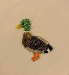 a close up of a bird on a white surface with beaded trimmings