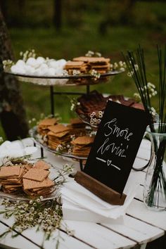 a table topped with lots of desserts on top of wooden tables covered in grass