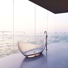 a bathtub sitting on top of a table next to the ocean