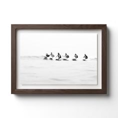 black and white photograph of surfers on surfboards in the ocean, framed in wood frame