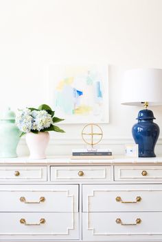 a white dresser topped with blue vases and flowers