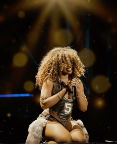 a woman sitting on top of a stage holding a microphone