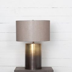 a lamp that is sitting on top of a wooden table next to a white wall