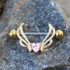 a gold nose ring with a pink stone in the center on top of a rock