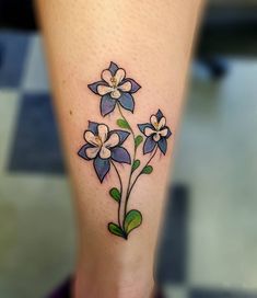 a flower tattoo on the leg of a woman's legs, with blue and white flowers