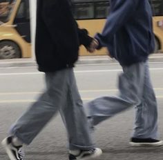 two people walking down the street with their feet in each other's pockets and holding hands