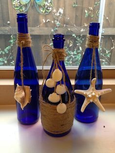 three blue glass bottles with seashells and starfish decorations