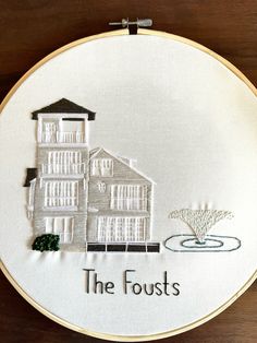 a white embroidered wall hanging with the words, the fosts and a house