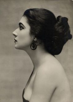 an old fashion photo of a woman with large earrings on her head, looking off to the side