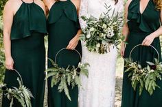 four bridesmaids in dark green dresses with greenery and flower arrangements on them