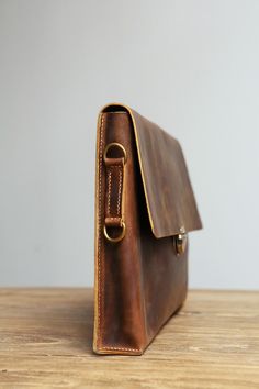 a brown leather bag sitting on top of a wooden table