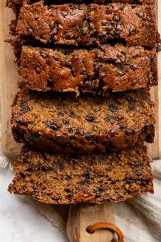 slices of chocolate chip banana bread stacked on top of each other next to a wooden spoon