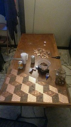 a wooden table topped with lots of different types of coins and cups on top of it