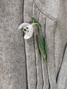 a white flower that is on the back of a gray shirt with green trims