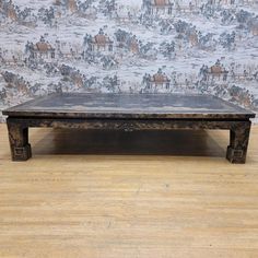 an old wooden coffee table sitting in front of a wall with a horse pattern on it