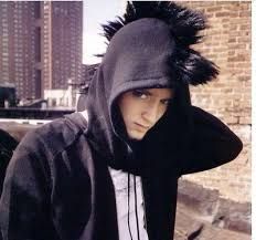 a young man wearing a black hoodie with furry ears on his head standing in front of a brick building