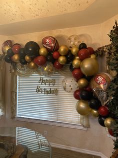 the balloon arch is decorated with black, gold and red balloons