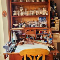 a wooden desk topped with lots of crafting supplies and jars on top of it