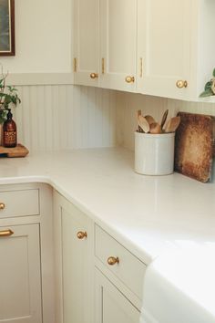 a kitchen with white cabinets and gold handles