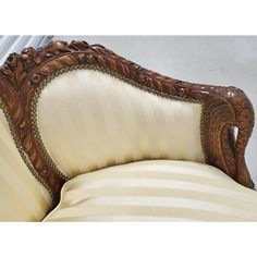 an ornately carved wooden arm chair with striped upholstered fabric and gold trimmings