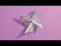 an origami airplane made out of money on a pink background