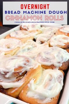 cinnamon rolls with white icing in a baking dish on a blue and yellow striped towel