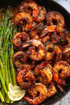 grilled shrimp and asparagus in a skillet with lemon wedges