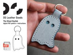 a hand holding a leather keychain with a ghost design on it and the text ds leather goods