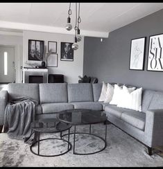 a living room with grey couches and pictures on the wall above them, along with two tables