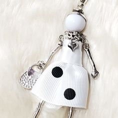 a white key chain with a black and white polka dot doll on it's back