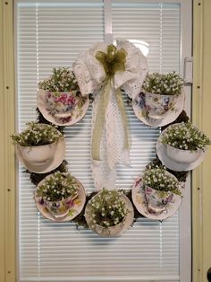 a wreath made out of teacups and saucers with flowers on the front