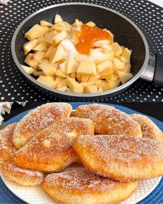 powdered sugar covered donuts on a plate next to a bowl of fruit