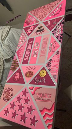 a pink box with stickers on it sitting on top of a white bed sheet