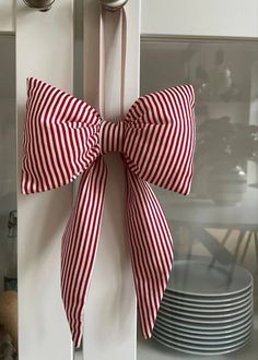 a red and white bow hanging on the side of a kitchen door with plates in the background