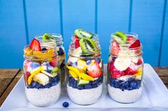 four mason jars filled with different types of fruit and veggies on a tray