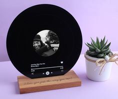 a wooden stand with a photo on it next to a succulent potted plant